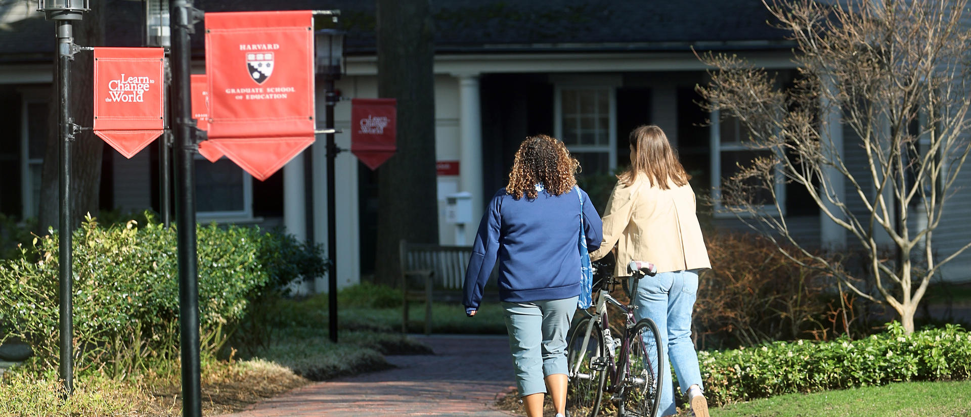 Students walking by HGSE signs outside of Gutman Library